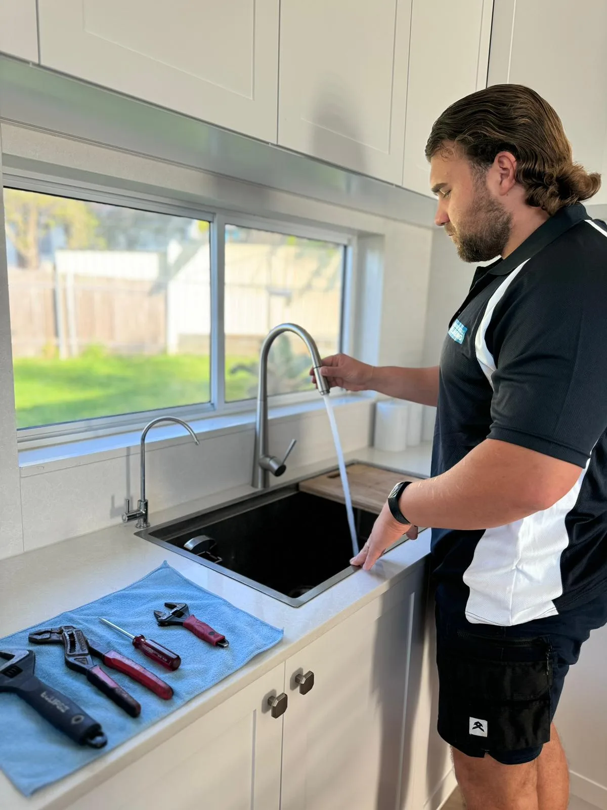 Plumber checking flow at a slow-draining kitchen sink